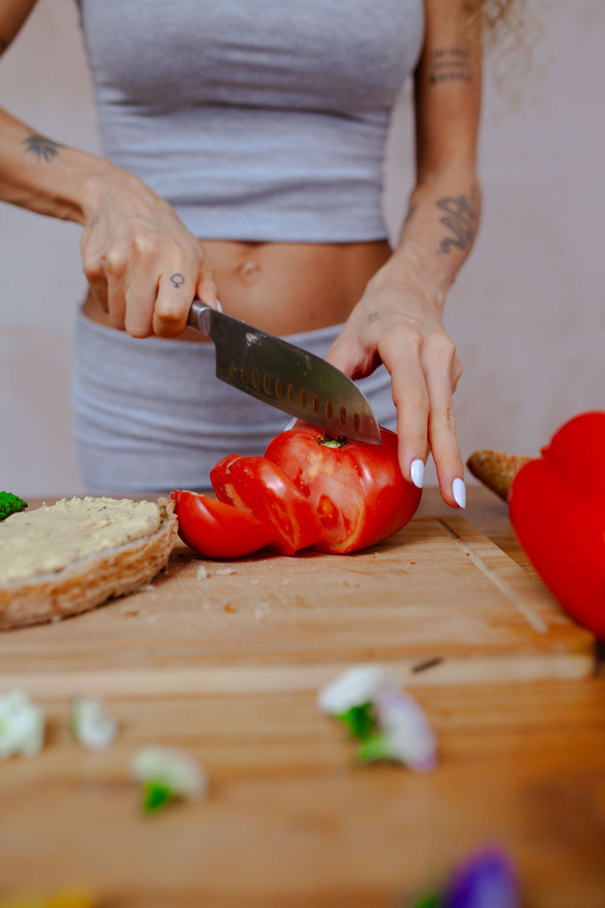 Image showing coahc's hands cutting tomatoe to prepare a healthy meal.